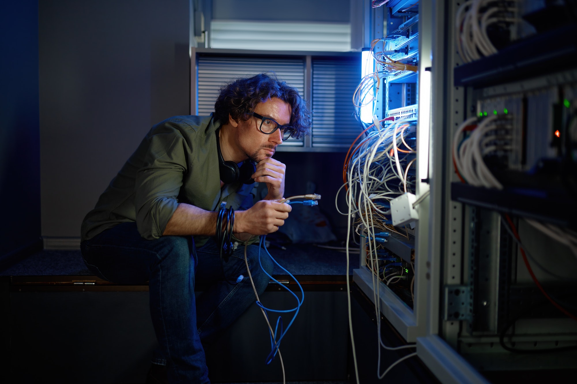 Male network engineer connecting cables in server room